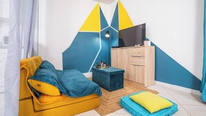 Een moderne kamer met een bank, een kleine tafel, een televisie en een kast.