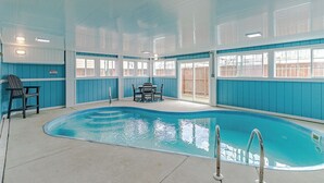 Ein Innenpool mit blau-weißer Farbgestaltung, einem Tisch, Stühlen und einem Sessel.