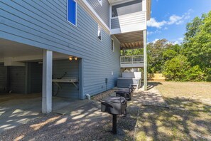 A covered outdoor area with a barbecue grill, seating, and a covered deck. - Sun Realty pet-friendly oceanside Duck home with hot tub (Duck)