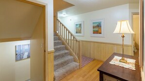 Eine Treppe führt zu einer zweiten Etage, ein Holzboden, eine Wand mit gerahmten Kunstwerken und ein Tisch mit einer Lampe.