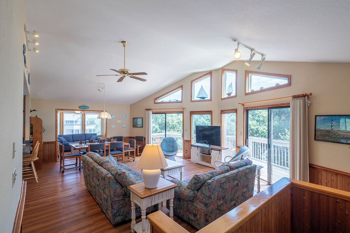 A spacious living room with a sofa set, a television, and a dining area with chairs and a table.