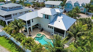 A large, multi-story house with a swimming pool surrounded by palm trees. - dreAMI - Luxury Island Home - Anna Maria - By Island Real Estate (Holmes Beach)
