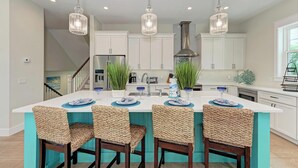 A modern kitchen with a central island, white cabinetry, and pendant lighting. - dreAMI - Luxury Island Home - Anna Maria - By Island Real Estate (Holmes Beach)