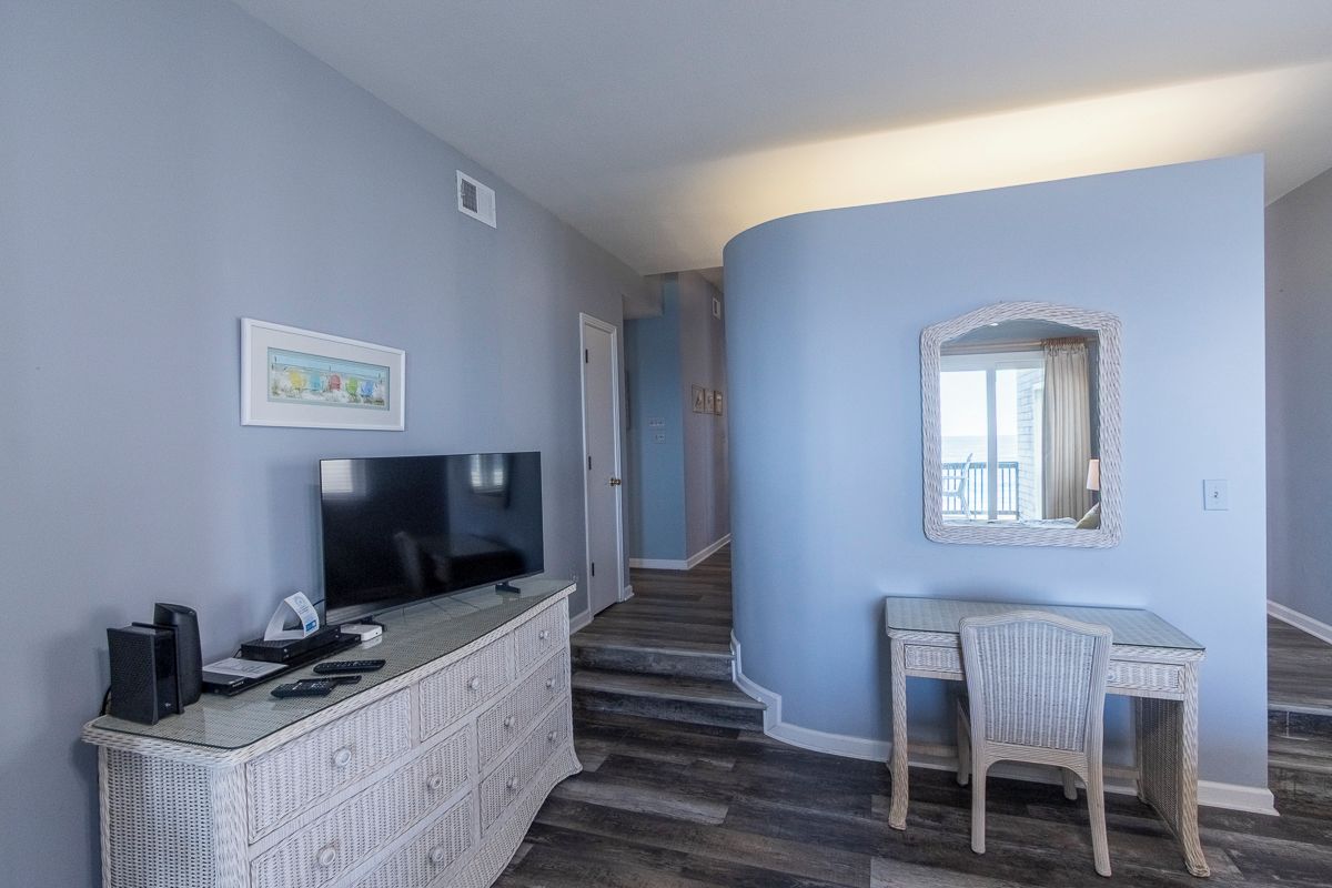 A room with a television, a desk, and a chair.