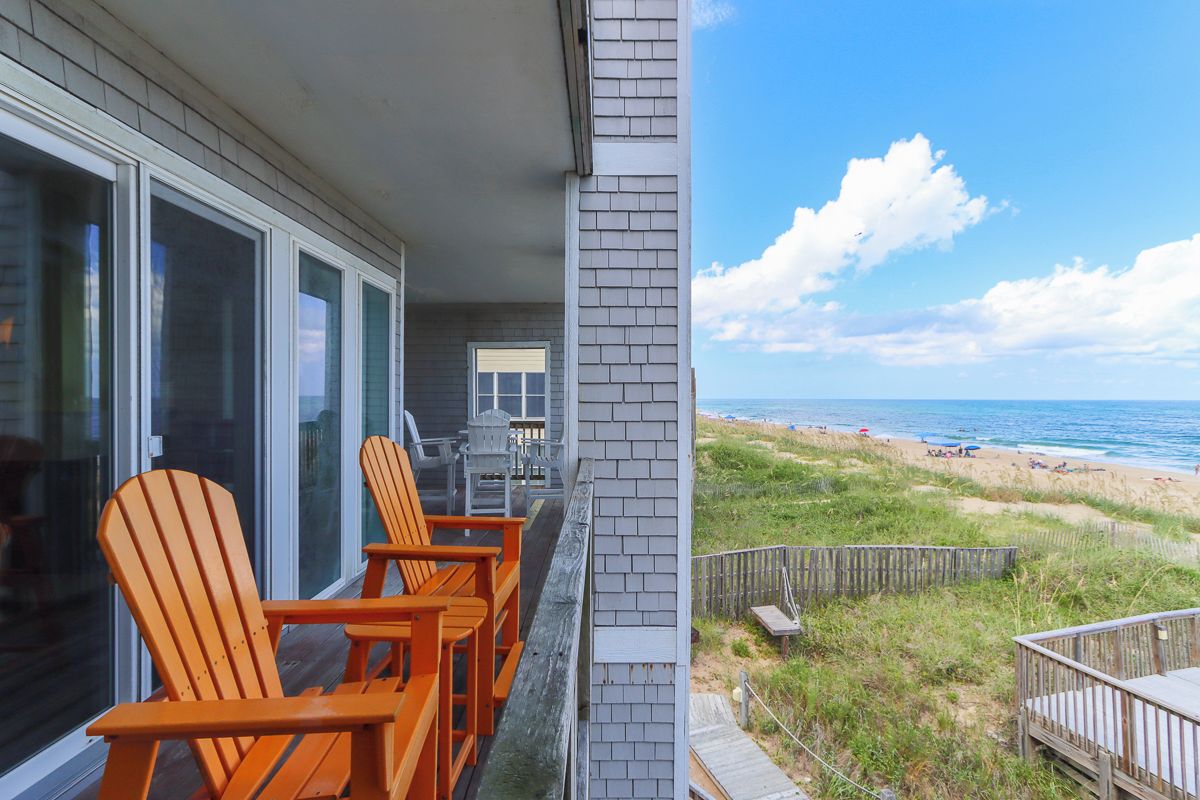 A beachfront property with a balcony, outdoor seating, and a view of the beach.