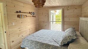 Un dormitorio de cabaña de madera con una cama, una lámpara colgante y una ventana.