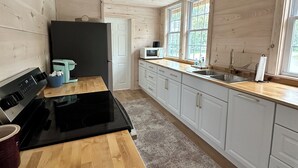 Una cocina amplia con gabinetes de madera, una estufa negra y una ventana con vistas a zonas verdes.