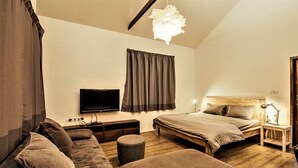 A bedroom with a large bed, a sofa, a TV, and a wooden floor. - Umalas Studio Near Canggu & Seminyak • Fast Wi-Fi + Kitchen (Badung Regency)