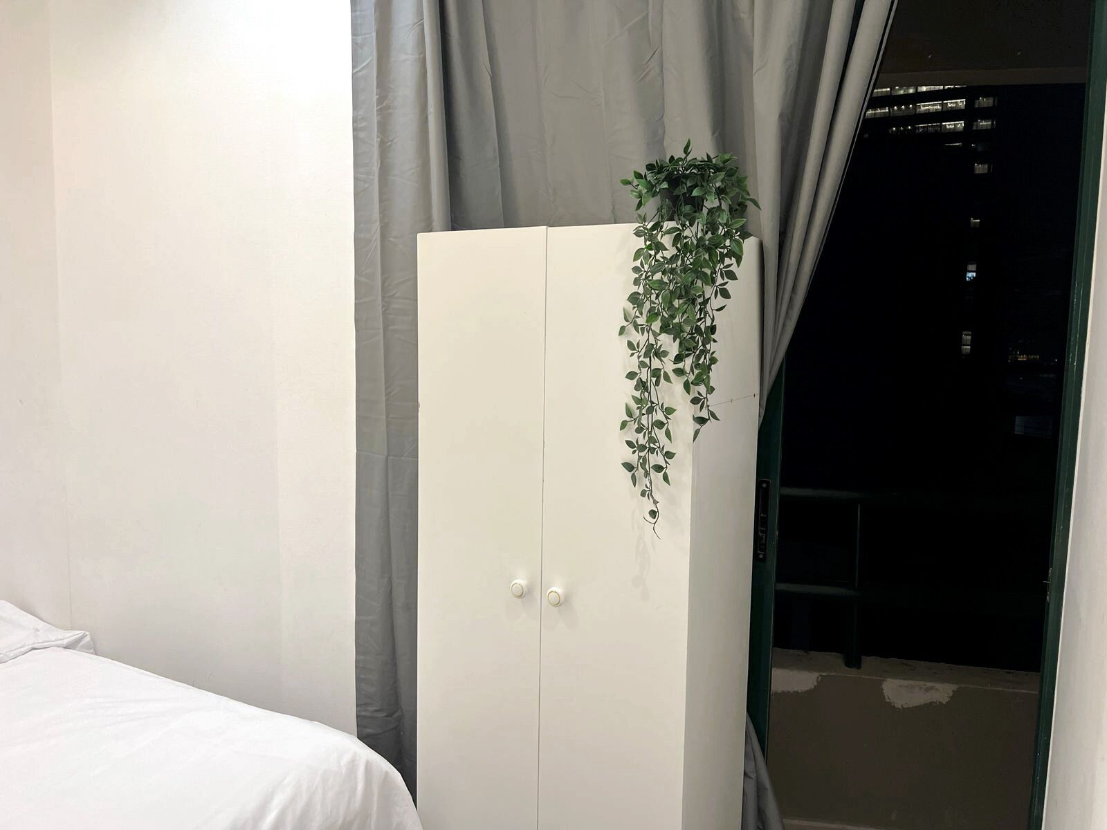 Un dormitorio con cama, armario y una planta colgante.