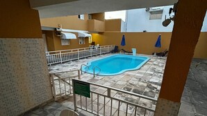 Ein Poolbereich mit Fliesenboden, einer Sitzbank und einem Schild mit Poolordnung.
