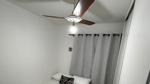 Ein Einzelbett mit grauer Decke, Kissen und Handtuch.