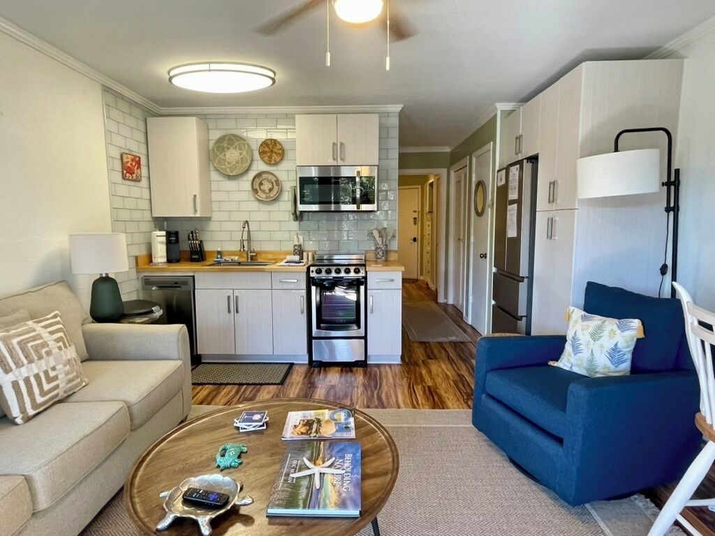 A compact living space with a kitchenette, a sofa, a coffee table, and a lamp.