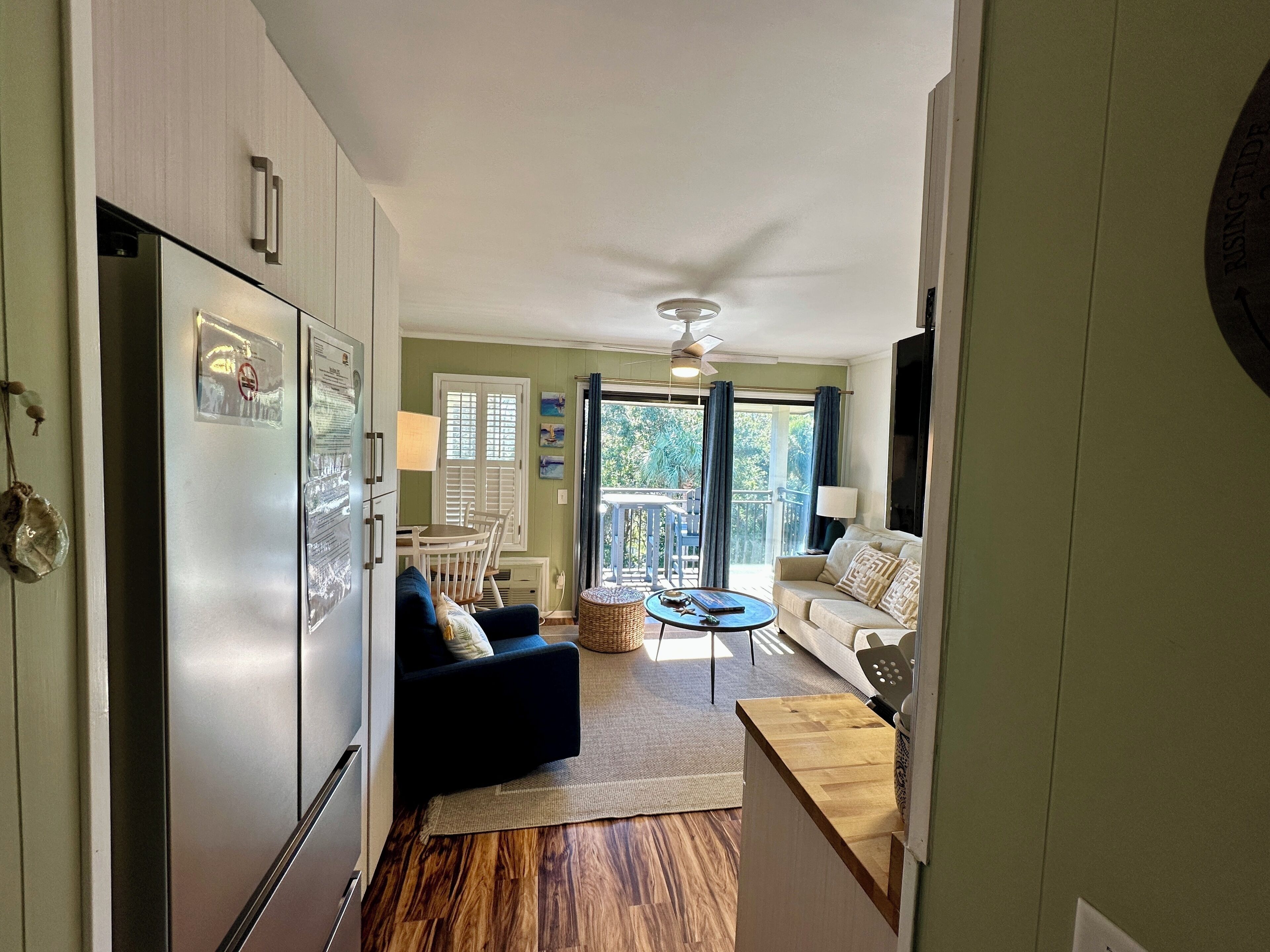 A compact kitchen with a refrigerator, a dining area with a table and chairs, a sofa, and a small coffee table.