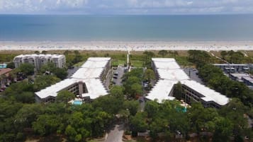 Vista aérea de un hotel con vista a la playa, que cuenta con varios edificios de techos planos rodeados de vegetación.