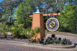 A sign for the Sanctuary at Redfish, surrounded by greenery and trees. - Penthouse with Gulf and Lake Views on 30A! (Santa Rosa Beach)