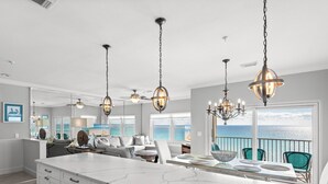 A spacious kitchen with a large island, modern pendant lights, and a view of the ocean. - Gulf Front Condo in Gated Crystal Beach Complex, End Unit (Destin)