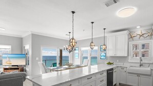 A modern kitchen with white cabinetry, a large island, and pendant lighting. - Gulf Front Condo in Gated Crystal Beach Complex, End Unit (Destin)