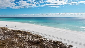 A beach with white sand and clear turquoise water under a partly cloudy sky. - Gulf Front Condo in Gated Crystal Beach Complex, End Unit (Destin)
