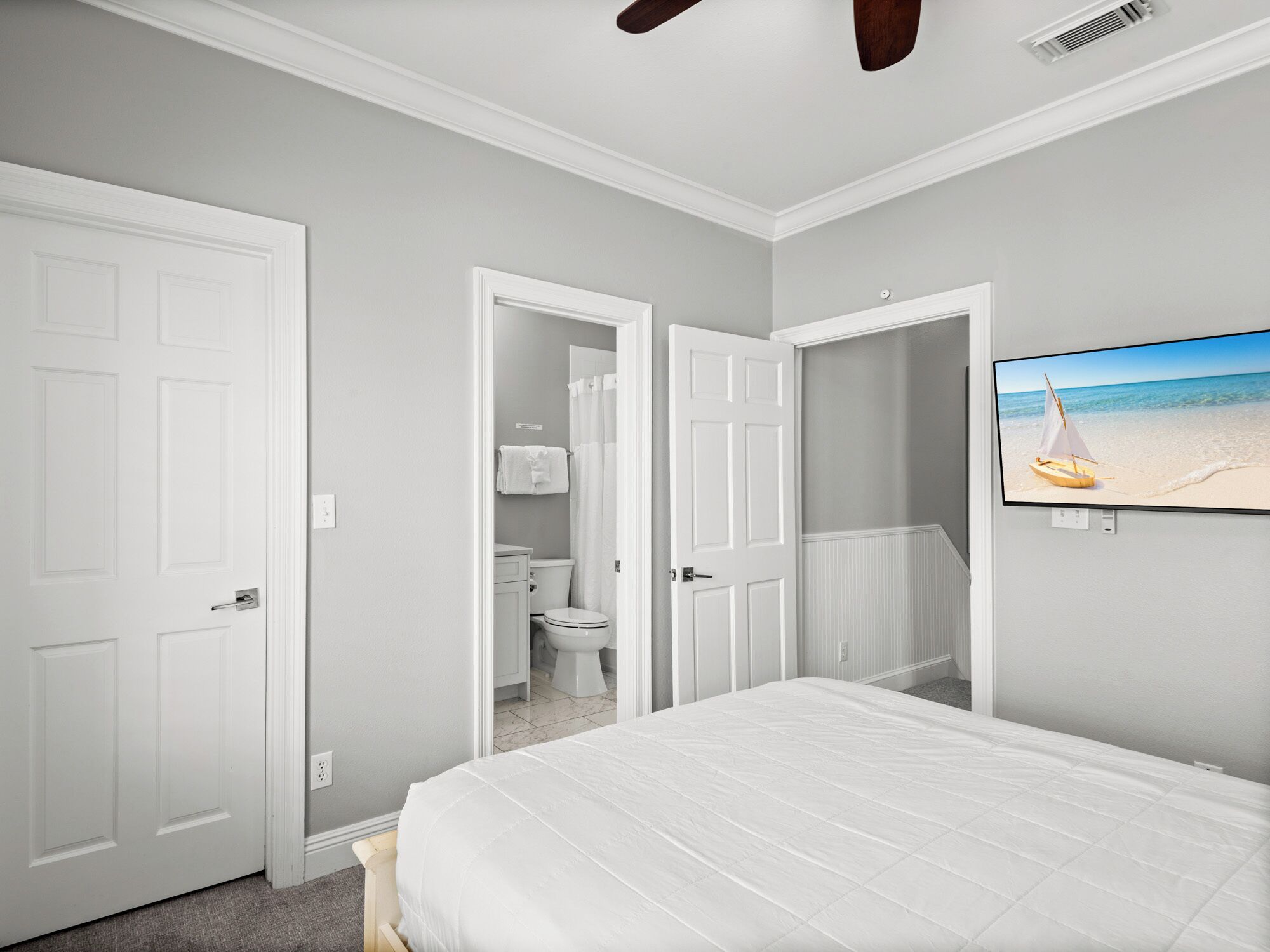 Un dormitorio con cama, baño y televisor en la pared.