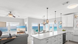 A modern kitchen with white cabinetry, a large island, and a view of the ocean. - Gulf Front Condo in Gated Crystal Beach Complex, End Unit (Destin)