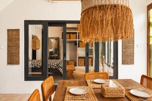 Ein Essbereich mit einem Holztisch, gewebten Tischsets und Korbstühlen.