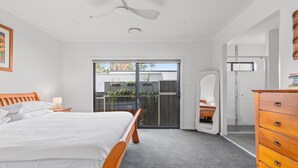 A bedroom with a bed, a dresser, a ceiling fan, and a sliding glass door leading to a balcony. - Bright Family Home in Rydalmere With Yard & BBQ (Sydney)
