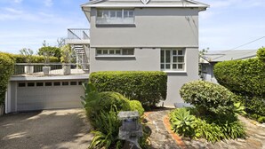 A two-story house with a garage, a stone pathway, and well-maintained greenery. - Spacious 5-bed Beach House With Ocean View (Sydney)