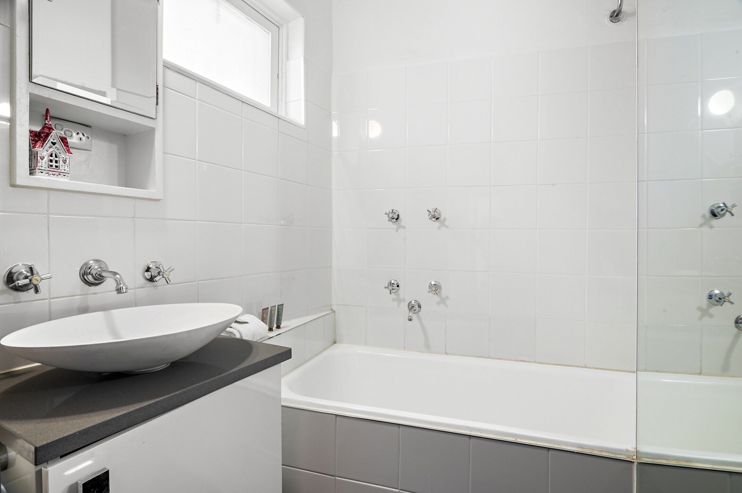 Un baño moderno con una bañera blanca grande, un lavabo sobremesa y un ventanal sobre el lavabo.