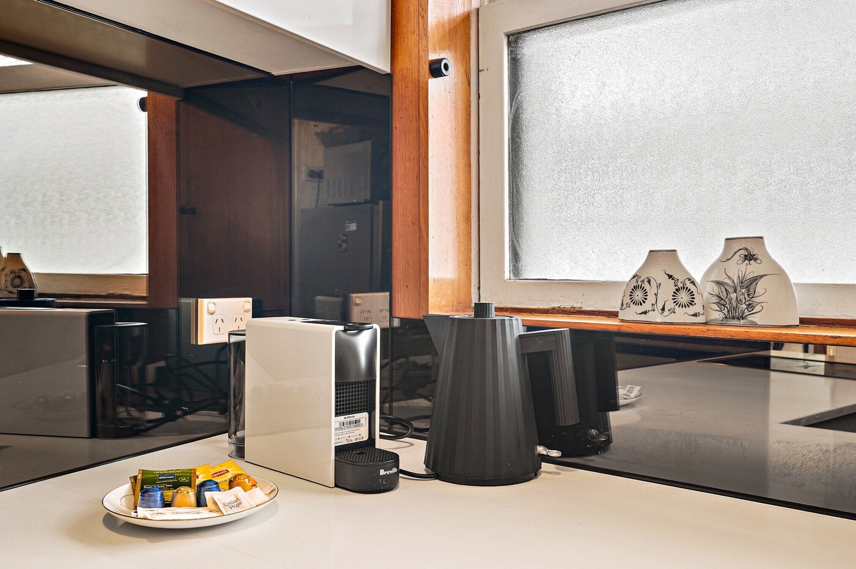 Una cocina moderna con una cafetera, un plato de aperitivos y jarrones decorativos en la encimera.
