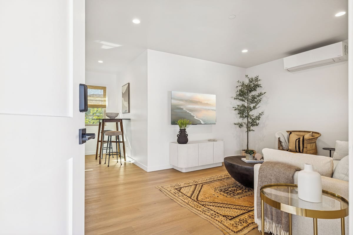 Un salon moderne avec un plancher en bois, un canapé, une table basse et un téléviseur fixé au mur.