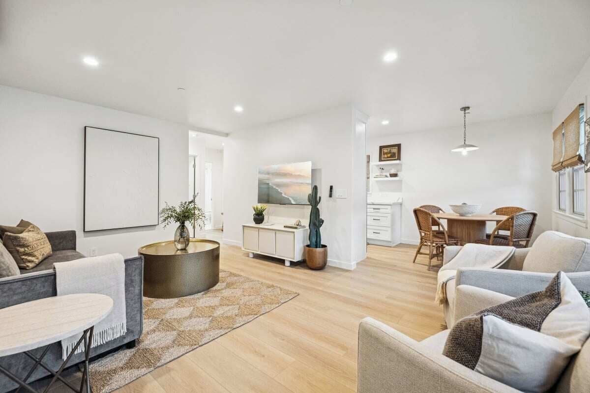 A modern living room with a sofa, a coffee table, and a dining area with chairs and a table.