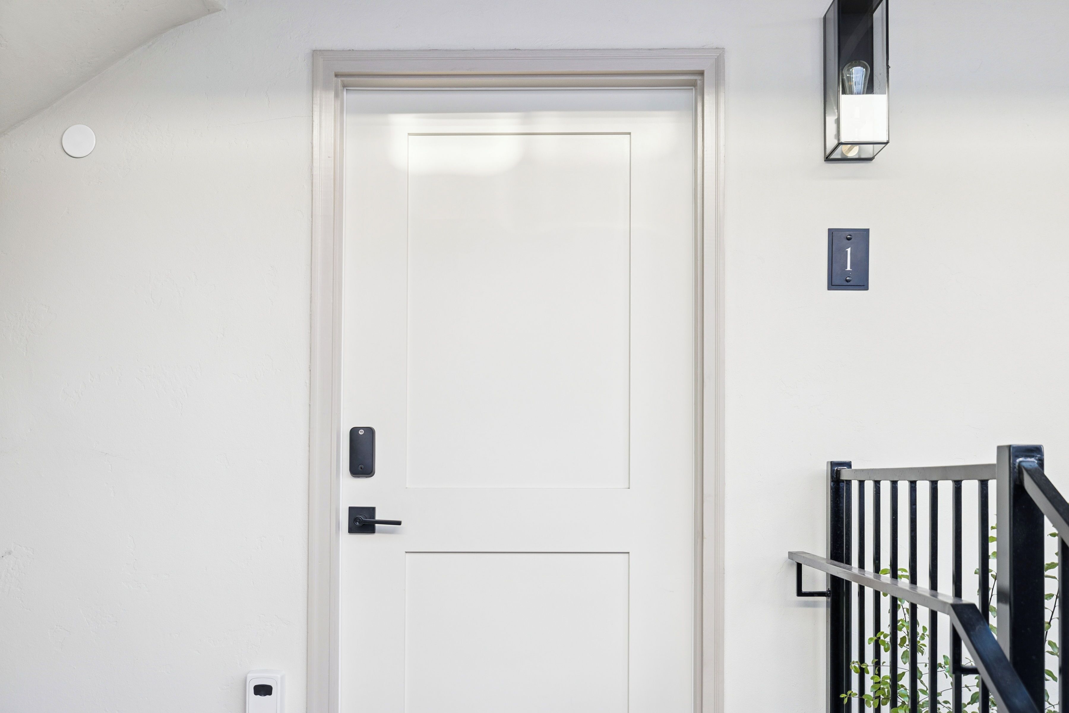A white door with a modern handle and a small light fixture above it.