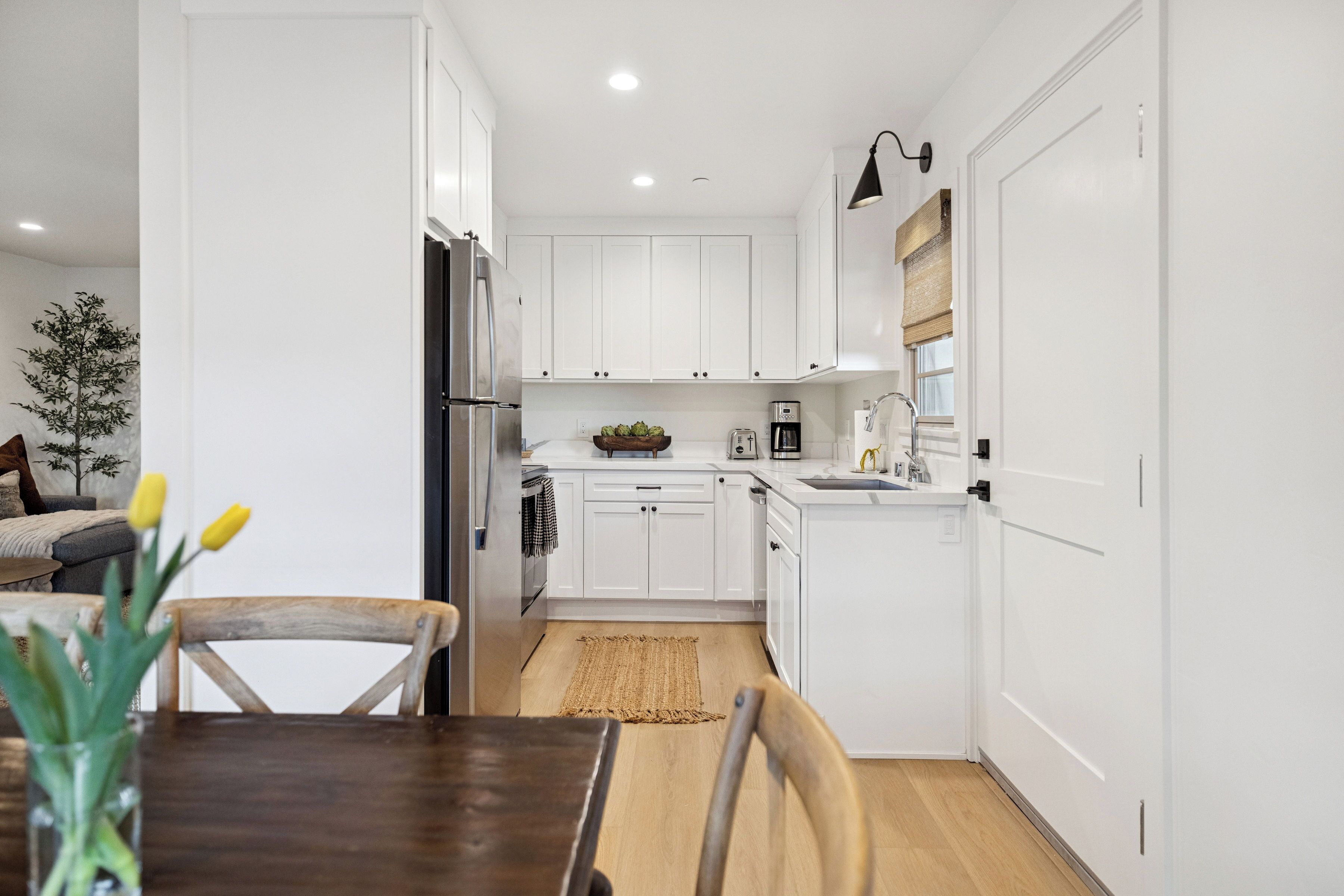 Una cocina moderna con armarios blancos, una mesa de comedor de madera y una pequeña alfombra.
