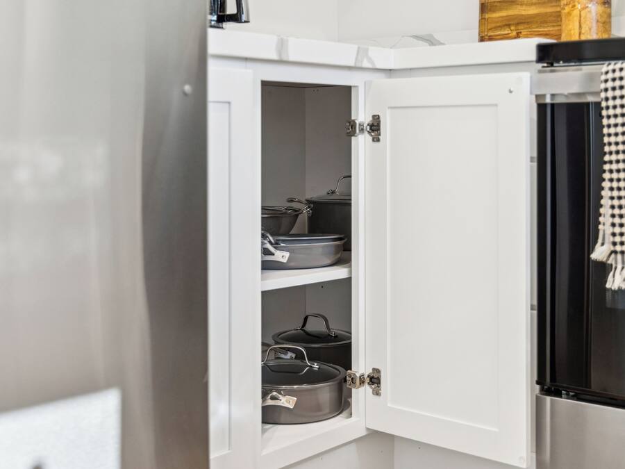 Um armário de cozinha com três prateleiras, cada uma com uma panela.