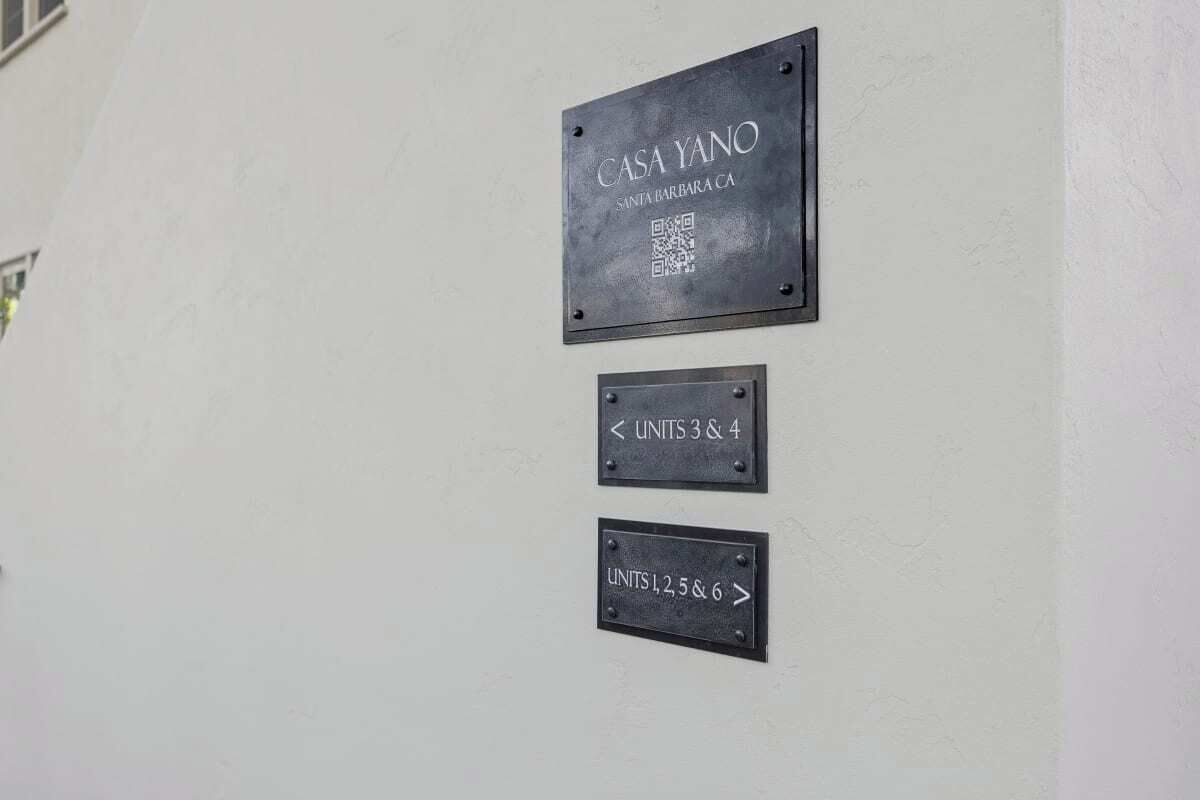 Un mur sur lequel sont affichées trois plaques indiquant les numéros des chambres : « CASA YANO SANTA BARBARA CA », « UNITÉS 3 ET 4 » et « UNITÉS 1, 2, 5 ET 6 ».