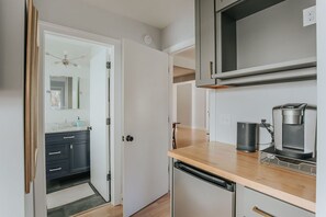 Eine moderne Küche mit einer Holzausziehtafel, einer Kaffeemaschine und einem Geschirrspüler.