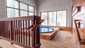 Une terrasse en bois avec un jacuzzi et une rambarde en bois.