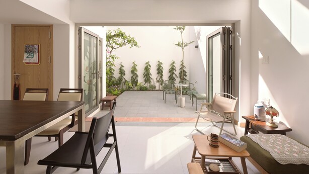 Un apartamento moderno con comedor, un pequeño espacio de descanso y vista a un patio con plantas.