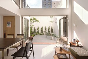 A modern apartment with a dining area, a small seating area, and a view of a courtyard with plants. - Gorgeous 4-bedroom Townhome with Full AC in vibrant Đà Nẵng (Đà Nẵng)