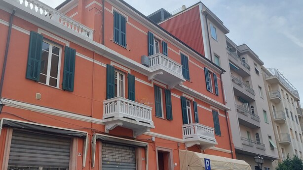 A multi-story building with balconies, a no parking sign, and a closed shuttered ground floor entrance. - Central and spacious apartment 100m from the sea! (Alassio)