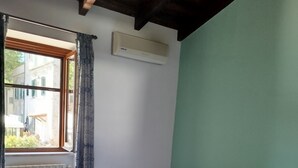 A bedroom with a bed, a radiator, a window with curtains, and a wall-mounted air conditioner. - Gabry House - sunset on the lake (anguillara sabazia)