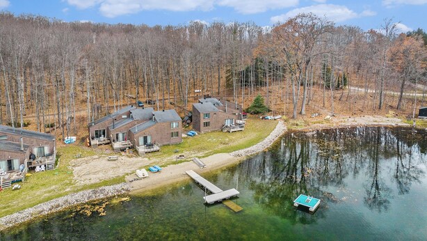 A lakeside cabin area with multiple cabins, a dock, and a boat. - Serene Northern Michigan 3-bedroom townhome near Boyne Mountain and Gaylord (Gaylord)
