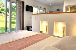 Ein modernes Hotelzimmer mit einem großen Bett, einem an der Wand befestigten Fernseher und Blick ins Freie durch die Fenster.