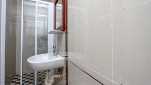 A bathroom with a glass shower enclosure, a white sink, and a tiled floor. - PLM Golden Lodge (Berea)