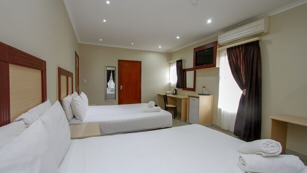 A hotel room with two beds, a desk, a mirror, and a small kitchenette. - PLM Golden Lodge (Berea)