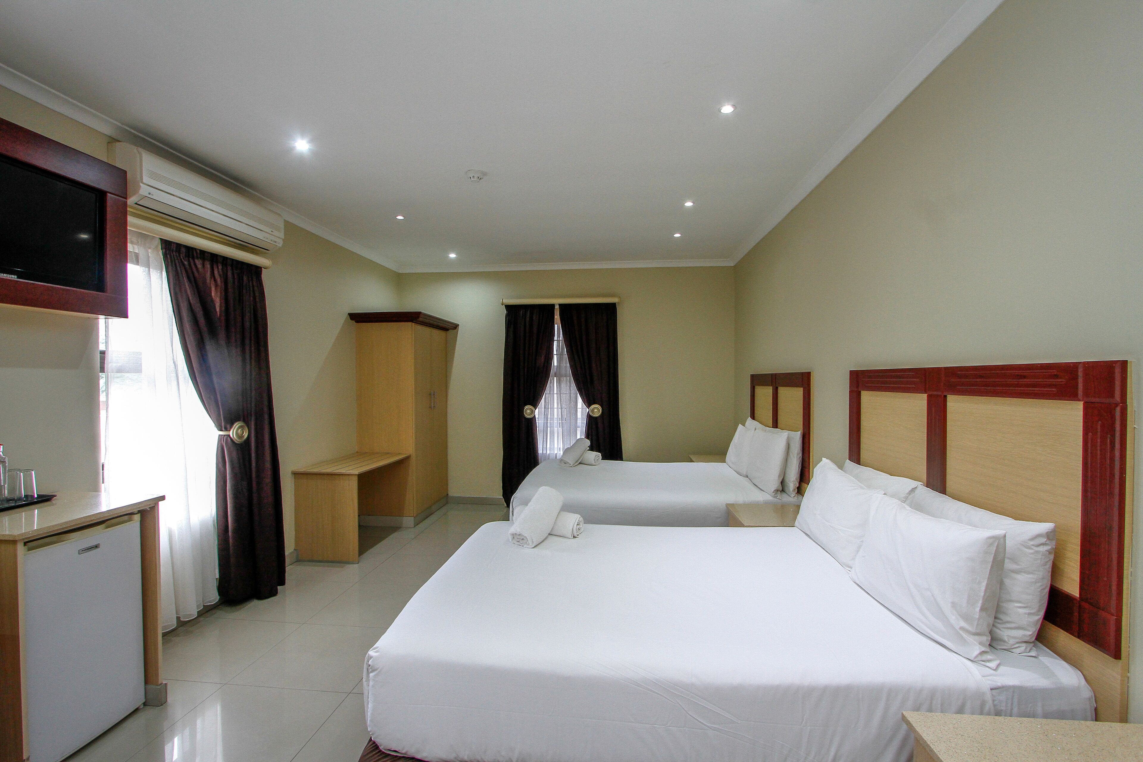 Habitación de hotel con dos camas, un escritorio, un televisor y un equipo de aire acondicionado.