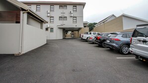 A parking lot with several parked cars and a building with multiple windows and air conditioning units. - PLM Golden Lodge (Berea)