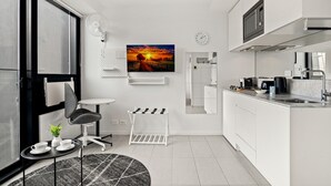 A modern kitchen with white cabinetry, a built-in microwave, and a large window. - South Melbourne Apartment With Gym Access (Melbourne)
