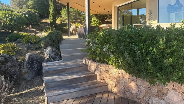 Ein modernes Haus mit einer Steintreppe, die zu einer überdachten Veranda führt.