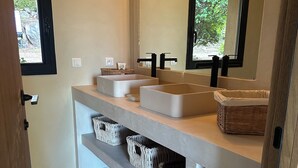 Ein Badezimmer mit zwei Waschbecken, einem großen Spiegel und Körben aus Weidengeflecht auf der Ablagefläche.